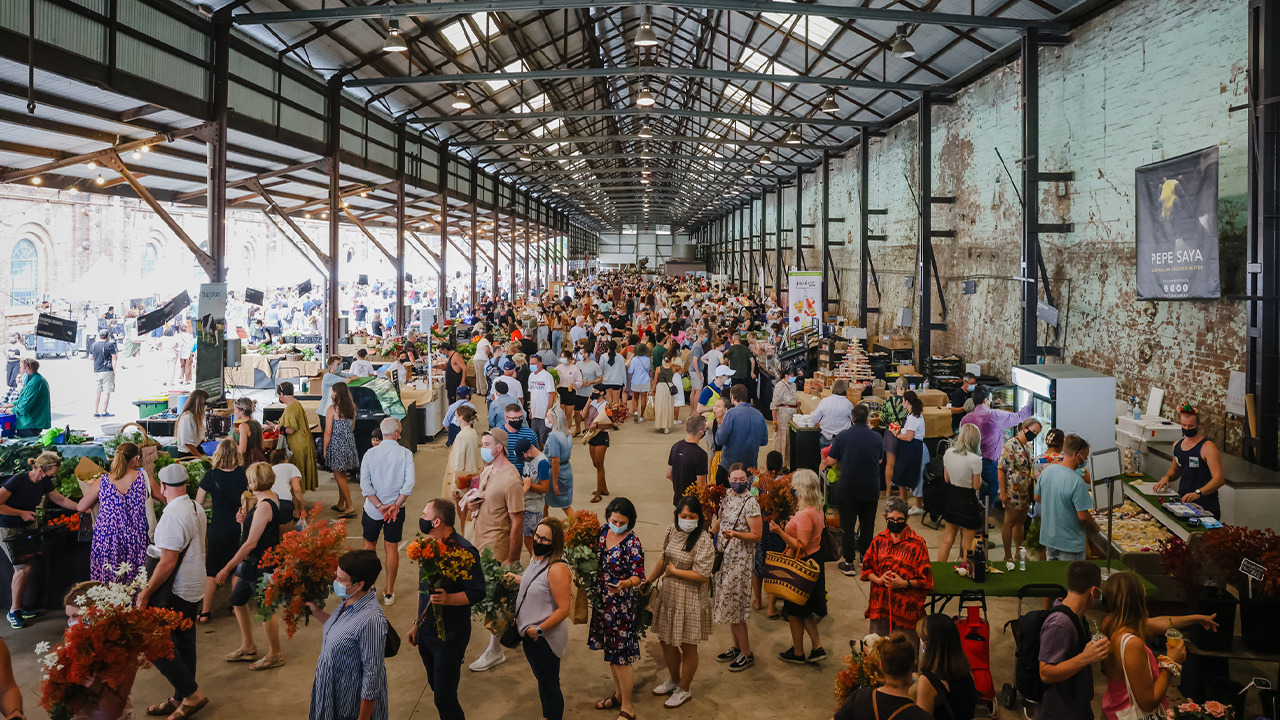 A crowd gathers in the Blacksmiths Workshop for the Carriageworks Farmers Market.