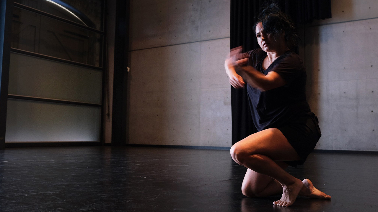 Henrietta Baird kneeling while dancing at Carriageworks