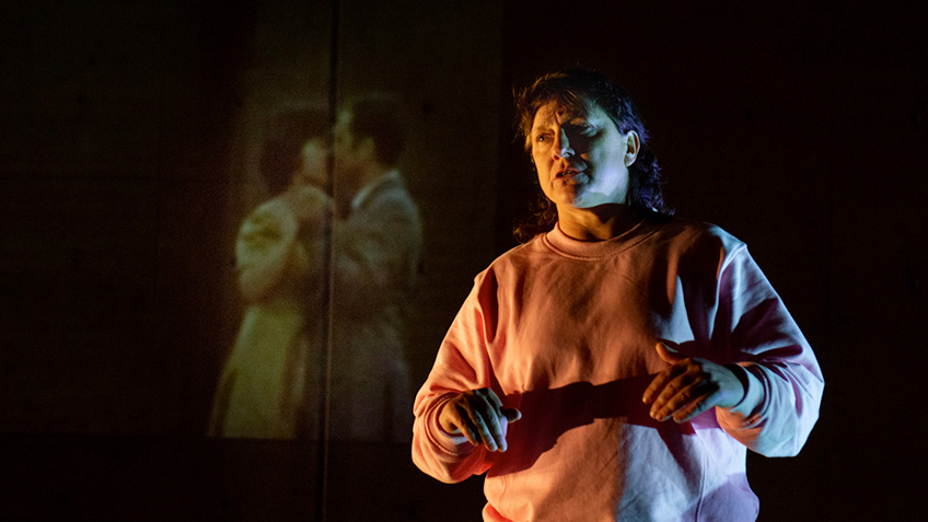 Kaz Therese in Sleeplessness in front of a projection of a couple.