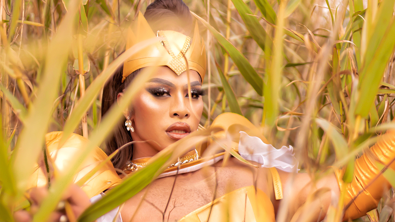 Kween Kong in gold outfit staring directly into camera.