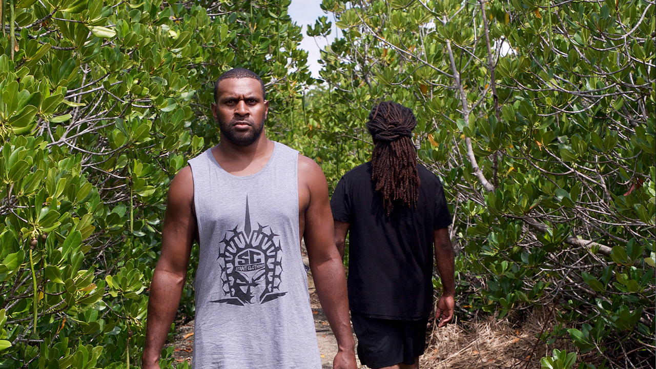 Two men walk away from each other bare foot on a path