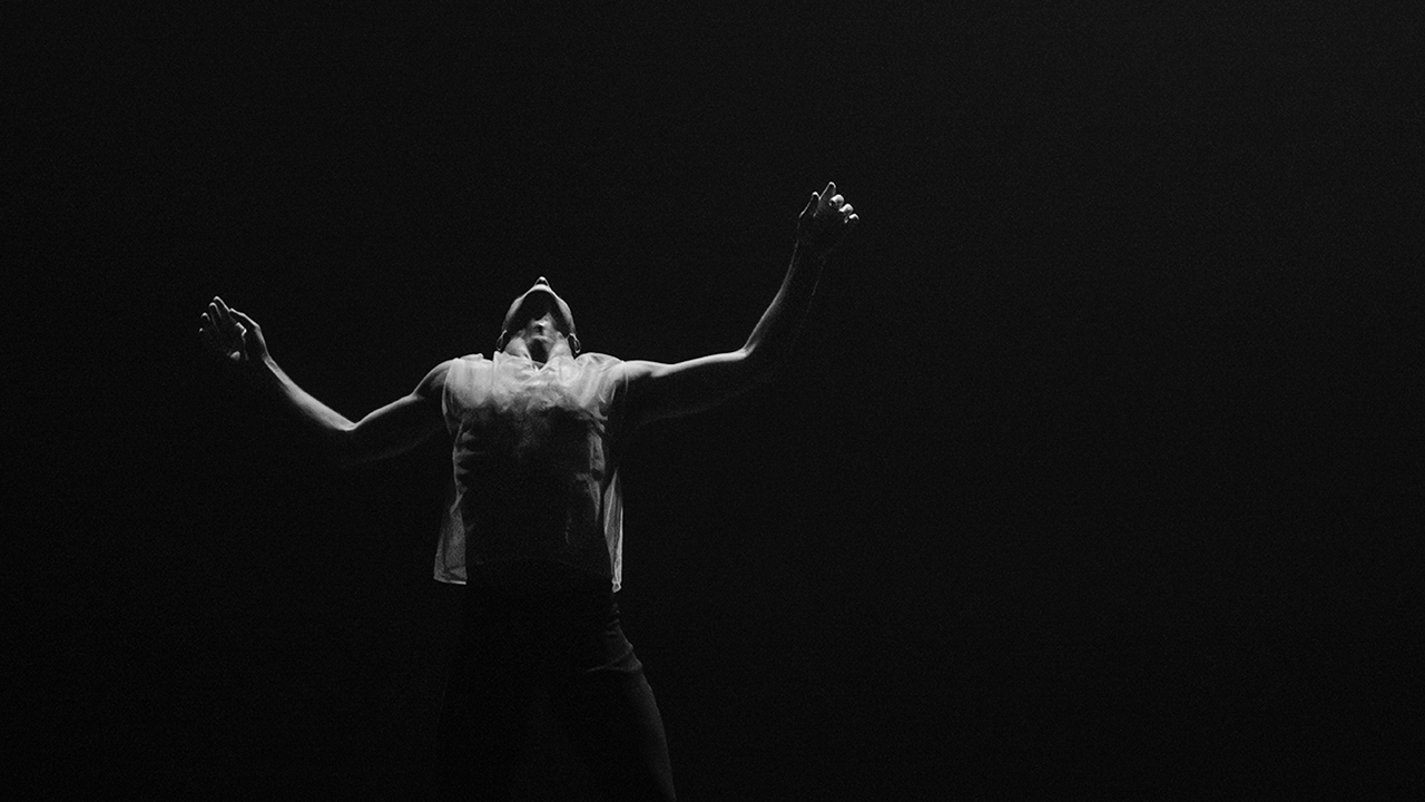 Black and white image of dancer on stage with arms outspread
