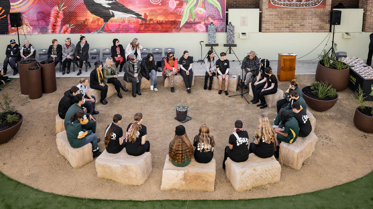A group of people sit in a circle at Evans High School.